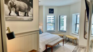 A bedroom with a bed, bench, and a wall-mounted picture of an elephant. - Modern Fully Renovated Loft in Downtown Trenton (Trenton)