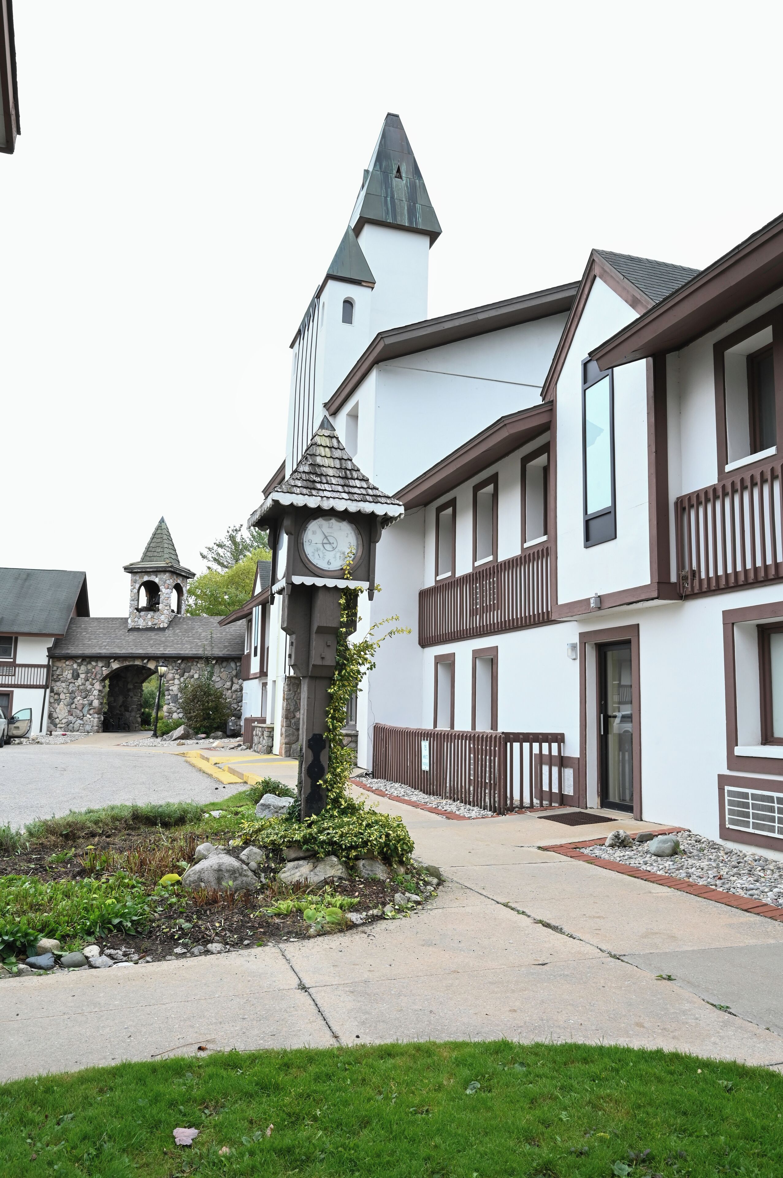 A building with a clock tower, stone archway, and a small garden area.