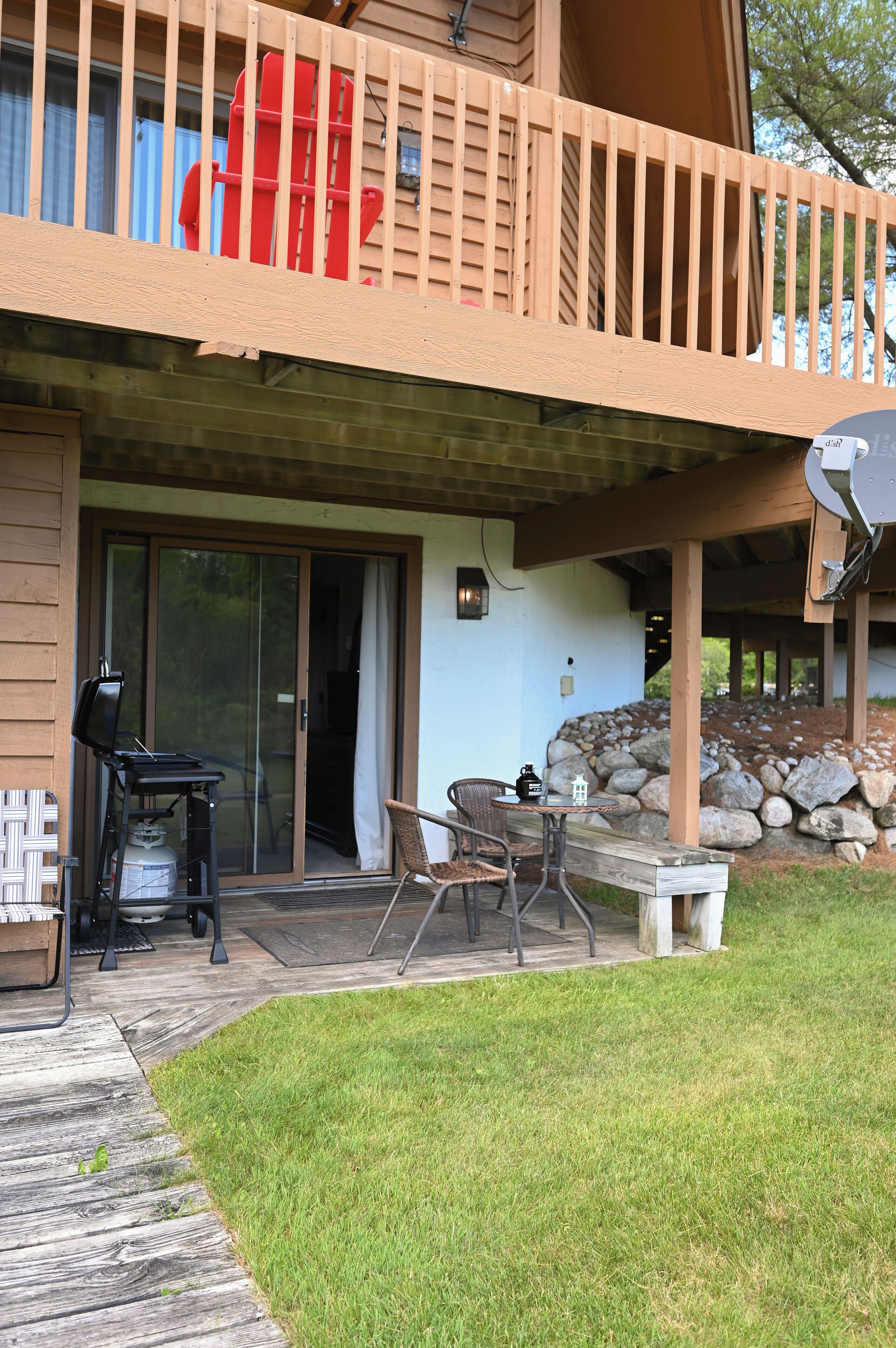 A covered patio with a grill, outdoor seating, and a view of the backyard.