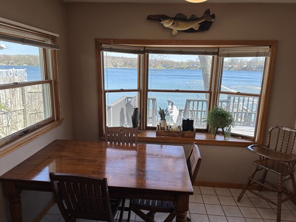 A dining area with a large table and chairs, a view of a lake, and a wooden fish decoration on the wall.