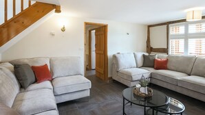 A living room with two sofas, a coffee table, and a staircase. - 3 bedroom accommodation in Church Stretton (Church Stretton)