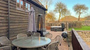 A patio with wicker furniture, a round table, a fire pit, and a hot tub. - 3 bedroom accommodation in Church Stretton (Church Stretton)