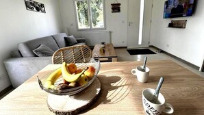 Una sala de estar moderna con un sofá gris, una mesa de centro de madera, un frutero y un televisor montado en la pared.