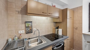 A modern kitchen with wooden cabinets, a stainless steel sink, an induction cooktop, and a built-in oven. - 2 bedroom stunning apartment in Malberg (Malberg)