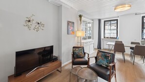 A modern living room with a flat-screen TV, wooden furniture, and a dining area with chairs and a table. - 2 bedroom stunning apartment in Malberg (Malberg)