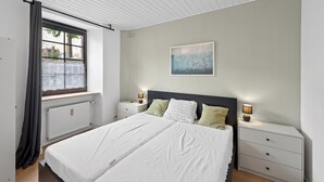 A bedroom with a bed, two bedside tables, a window with curtains, a radiator, and a painting on the wall. - 2 bedroom stunning apartment in Malberg (Malberg)