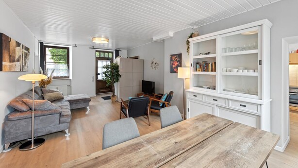 A modern living room with a wooden dining table, grey sofa, and a TV. - 2 bedroom stunning apartment in Malberg (Malberg)