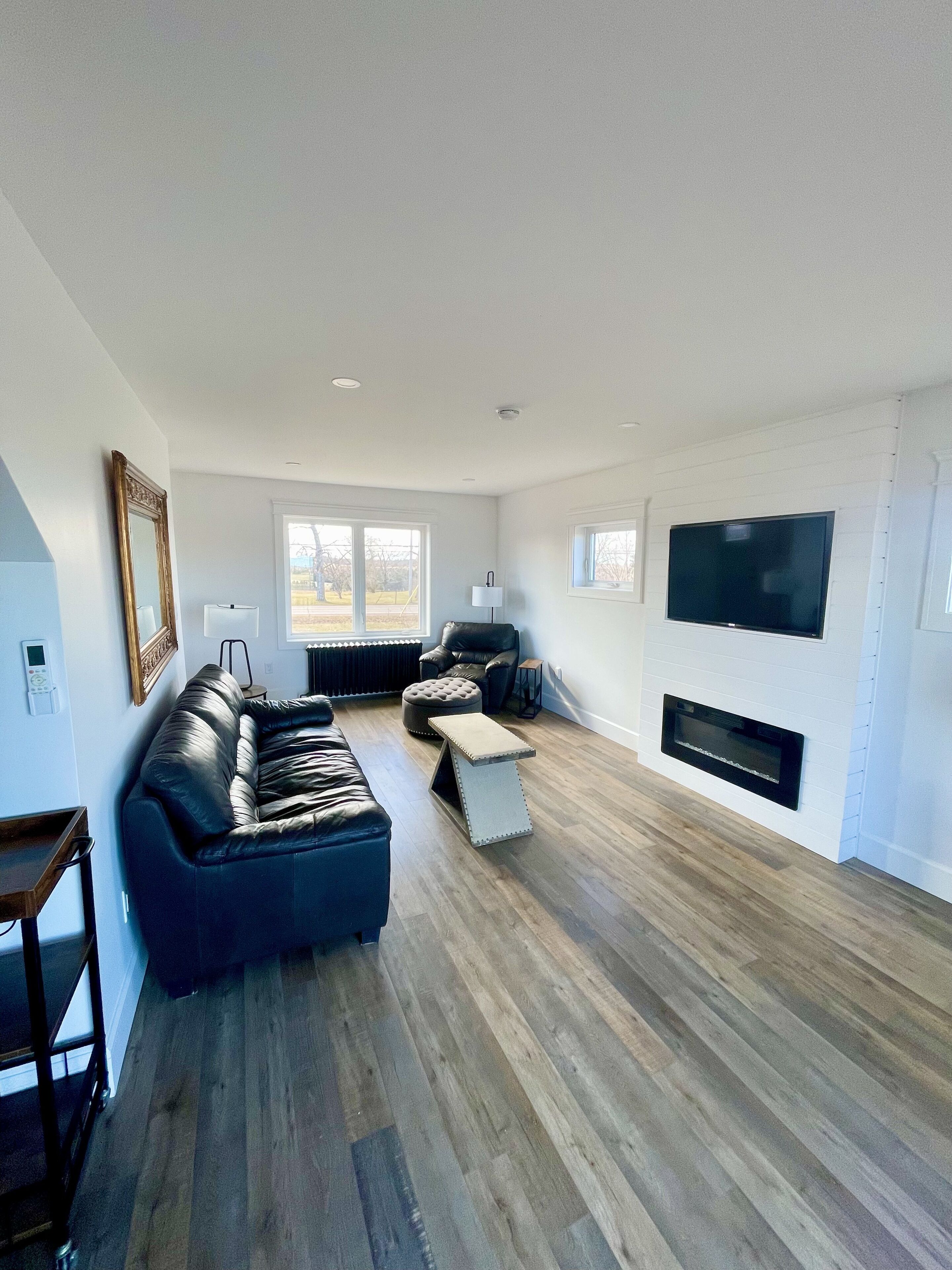 A modern living room with a sectional sofa, a fireplace, and a large TV mounted on the wall.