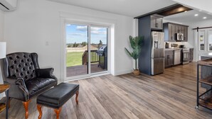 A modern kitchen with stainless steel appliances, a dining area with a wooden table, and a sliding glass door leading to a deck.
