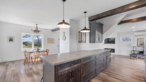 A spacious kitchen with a large island, dark wood cabinets, and pendant lighting.