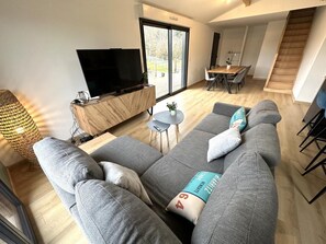 Relax in this stylish living room with a large sofa, flat-screen TV, and dining area.