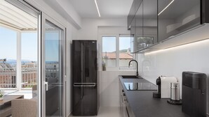 A modern kitchen with a black refrigerator, a sink, and a compact stove. - Athenian Riviera Penthouse Apartment (Vari)