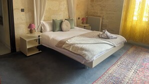 Ein Schlafzimmer mit einem großen Bett, zwei Nachttischen, einem Heizkörper und einem gemusterten Teppich.