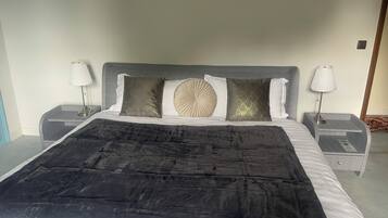 A neatly made bed with a black bedspread, two bedside tables with lamps, and decorative pillows.