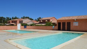Zwei rechteckige Schwimmbecken mit gefliesten Rändern, umgeben von einer niedrigen Mauer und einem gepflasterten Bereich.
