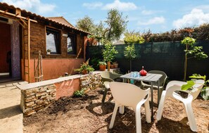 A patio with a table and chairs, surrounded by potted plants and a stone wall.