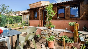 Ein Haus mit Steinuntergrund, Holzfassade und einer mit Kletterpflanzen bewachsenen Pergola.