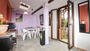 Ein Zimmer mit Esstisch, Stühlen, einer Uhr, einem Fenster und einer Schiebetür zu einem Außenbereich.