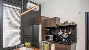 Una cocina moderna con refrigerador, microondas y estufa integrados. Cuenta con una mesa de comedor con sillas y una planta en maceta.