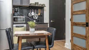 Una cocina compacta con armarios oscuros, un microondas, una cafetera y utensilios colgantes.