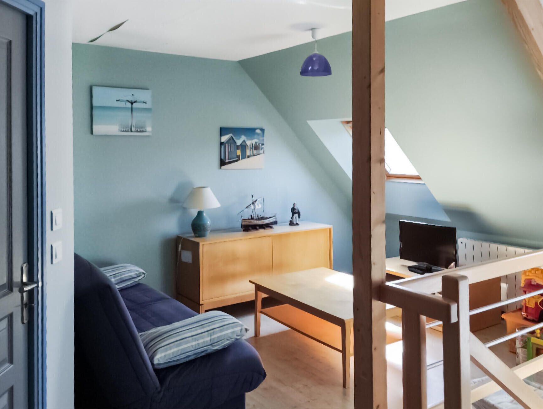 Un salon confortable avec un canapé, une table basse en bois et un téléviseur posé sur un meuble.