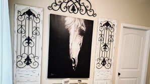 A bedroom with a bed, a wooden bench, a small table with a candle, and a large abstract painting on the wall. - Harbor Hideway is a cozy, romantic gem minutes away from Jamestown Marina! (Jamestown)