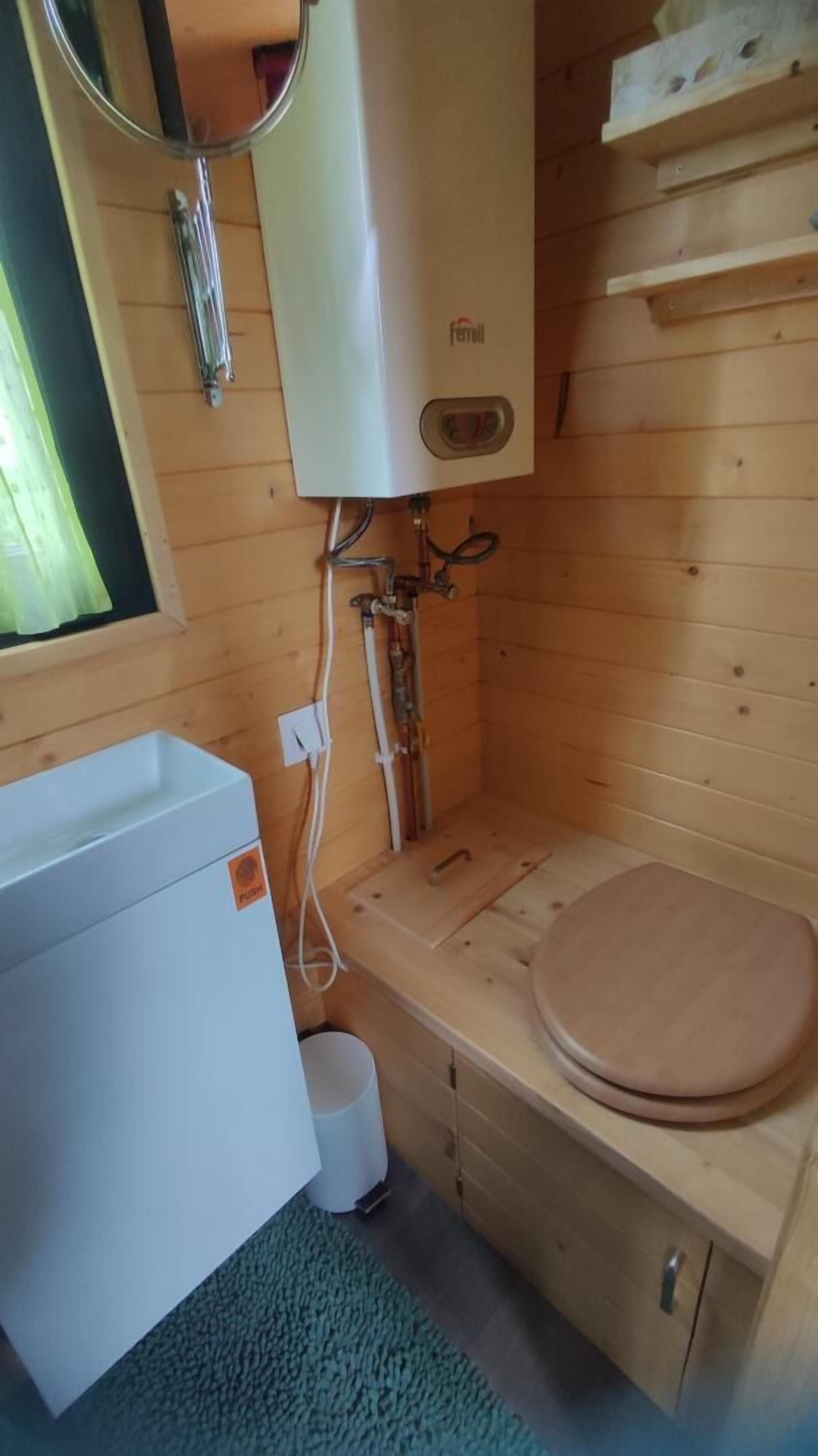 Un baño pequeño con inodoro blanco, lavamanos y un calentador de pared.