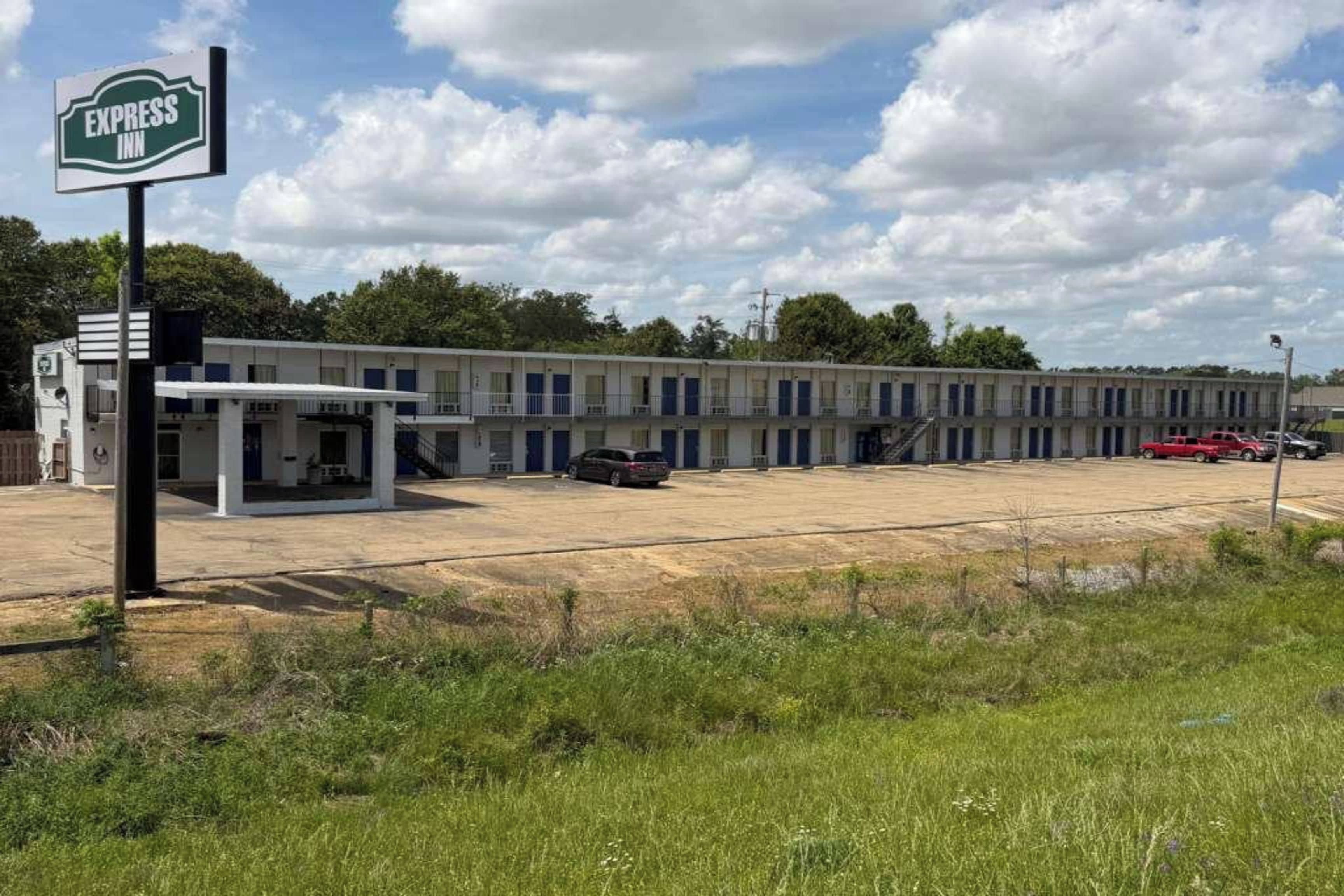 Un motel con una fila de habitaciones, un área de estacionamiento techada y un letrero que indica que es un Express Inn.