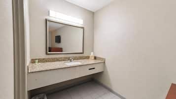 A bathroom with a sink, mirror, and trash can.