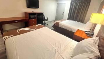 Une chambre d’hôtel avec deux lits, un bureau, une télévision et une lampe.