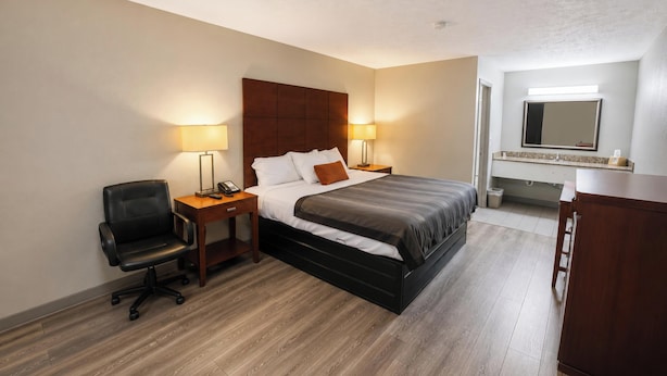 Een hotelkamer met een bed, nachtkastjes, een stoel, een bureau en een spiegel.