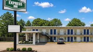 Een motel met een bord waarop 'EXPRESS INN' staat, een parkeerplaats en een gebouw met meerdere kamers.