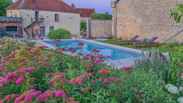 A swimming pool surrounded by lush greenery and a stone building. - Le Cottage - MAISONS LES CHAOURCE (MAISONS LES CHAOURCE)