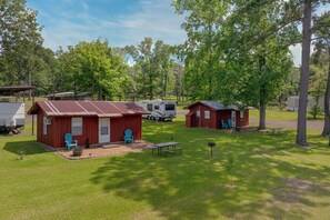 A campsite with RVs, wooden cabins, and picnic tables.