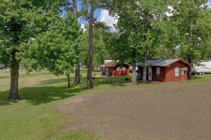 Un terrain de camping comprenant plusieurs cabanes en bois, des tables de pique-nique et un sentier de terre.
