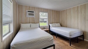 Ein Zimmer mit zwei Betten, einem Fenster und einem Deckenventilator.