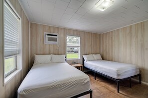 Una stanza con due letti, una finestra e un ventilatore a soffitto.
