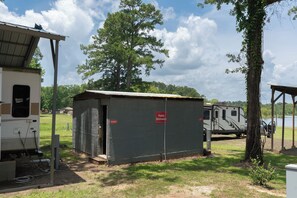 A campsite with RVs, a covered utility building, and a large tree.
