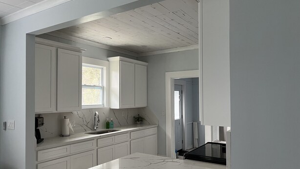 A kitchen with white cabinets, a marble countertop, and a window. - Relax at our Gulf Beach Retreat (Pensacola)