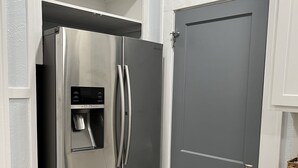 A stainless steel refrigerator with a water dispenser, a gray door, and a white countertop with a marble-like backsplash. - Relax at our Gulf Beach Retreat (Pensacola)