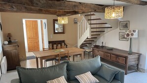 Un salon chaleureux avec un canapé vert, une table à manger en bois et un escalier.