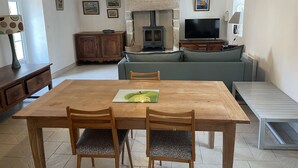 Un salon chaleureux avec une table à manger en bois, deux chaises, un canapé, un téléviseur et une cheminée.