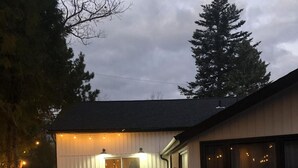 Une maison moderne avec un jacuzzi en premier plan, un patio couvert et une grande fenêtre.