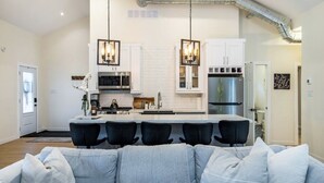 Une cuisine moderne avec des meubles blancs, un réfrigérateur en acier inoxydable et un îlot central doté de tabourets de bar.