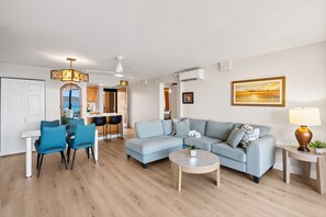 Una sala de estar moderna con un sofá, sillones, una mesa de centro y un comedor con mesa y sillas.