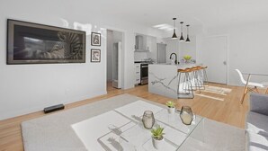 Una cocina moderna con armarios blancos, una isla de mármol e iluminación colgante.
