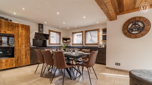A modern kitchen with a dining area, wooden cabinetry, and a clock on the wall. - Chalet Lamartine - Valloire (VALLOIRE)