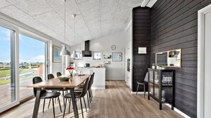 A modern kitchen with a large dining table, black chairs, and a view of the outdoors.