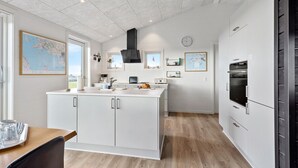 A modern kitchen with white cabinetry, a central island, and a built-in oven.