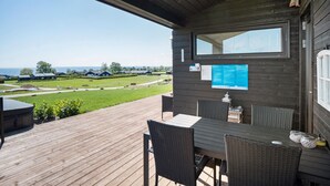 A wooden deck with a table and chairs, overlooking a grassy area with houses.